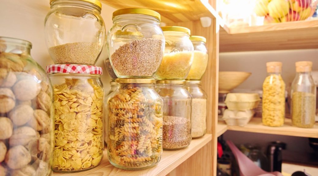 Petit placard bien organisé avec des bocaux, boîtes et provisions rangés sur plusieurs étagères.