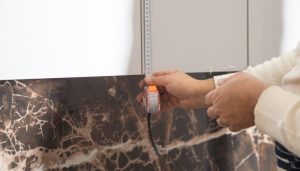 Locataire installant une protection murale derrière une plaque de cuisson dans une cuisine.