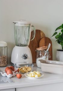 Robot pâtissier posé sur le plan de travail d’une cuisine, entouré de bols et d’accessoires de pâtisserie.